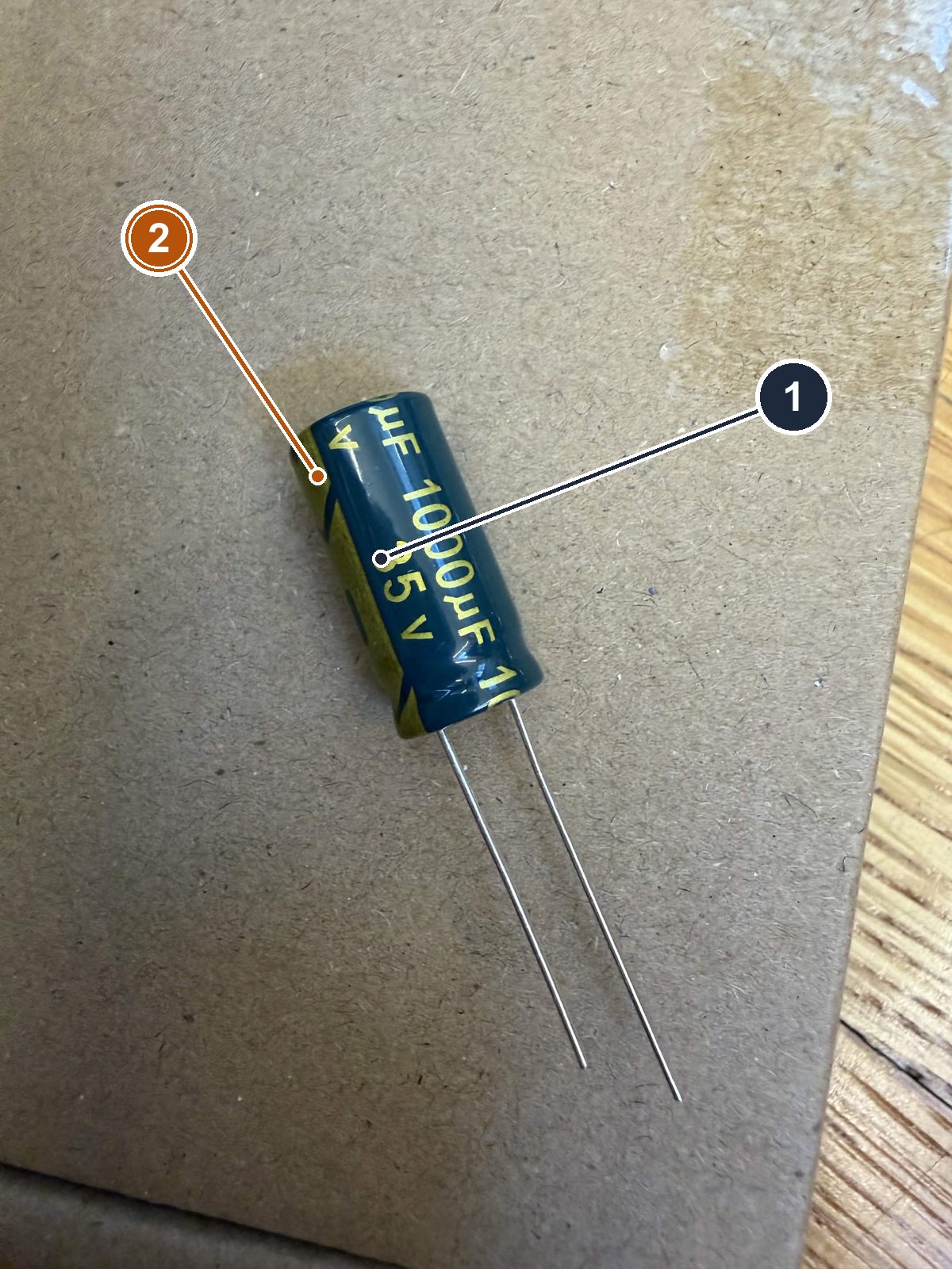 A 1000 microfarad 35 volt electrolytic capacitor with its negative-stripe marking