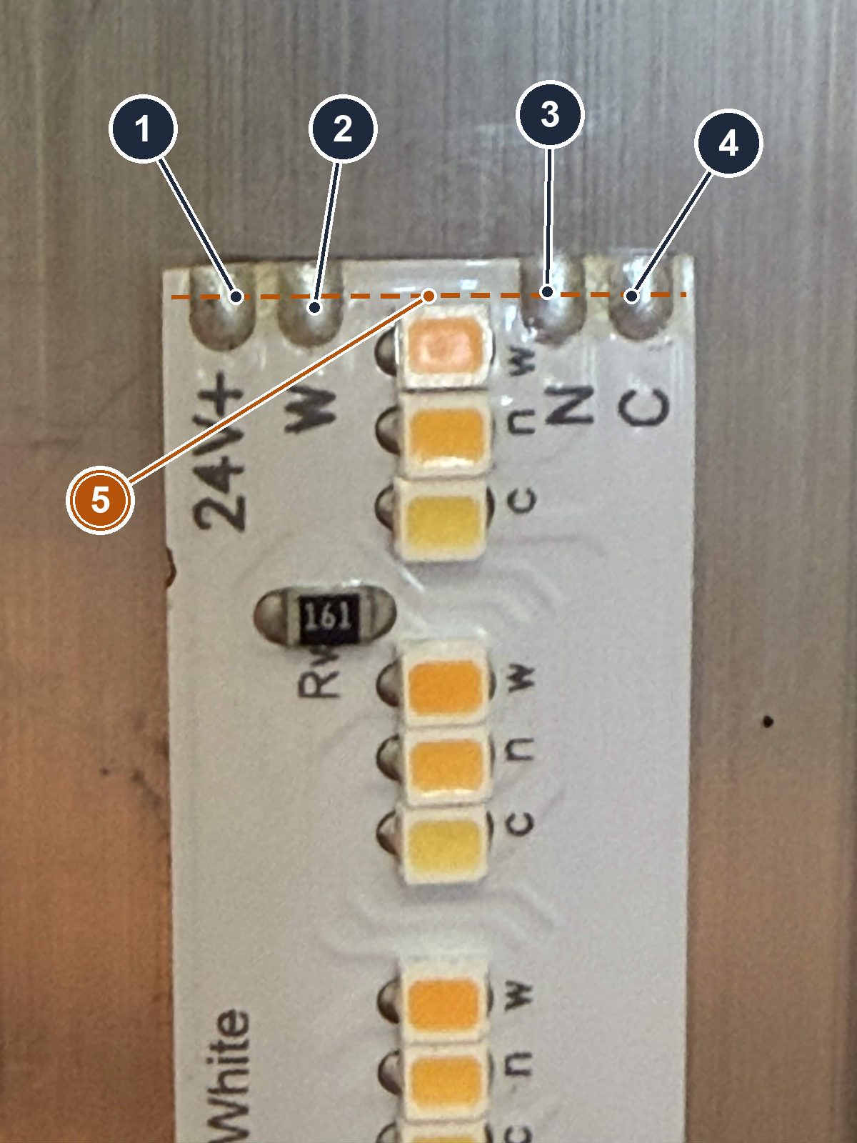 The Valent X tape at a cut line: four half-moon pads in a row, per-die letters beside each LED