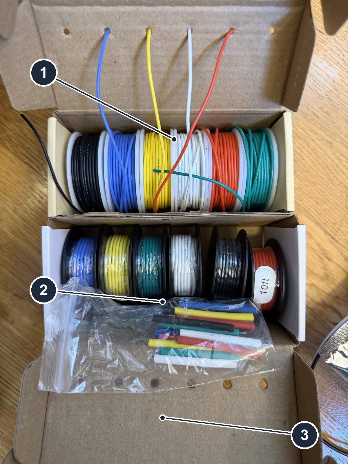 The two wire kits side by side: thin 24 AWG silicone spools and thicker 20 AWG spools, with a bag of heat-shrink